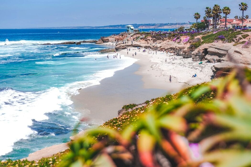 waves crashing on sandy beach with people places to visit in san diego