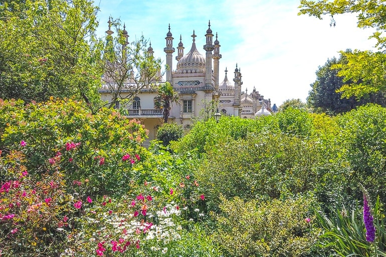 Grüne Gärten mit Blumen und Palast im Hintergrund in Brighton UK