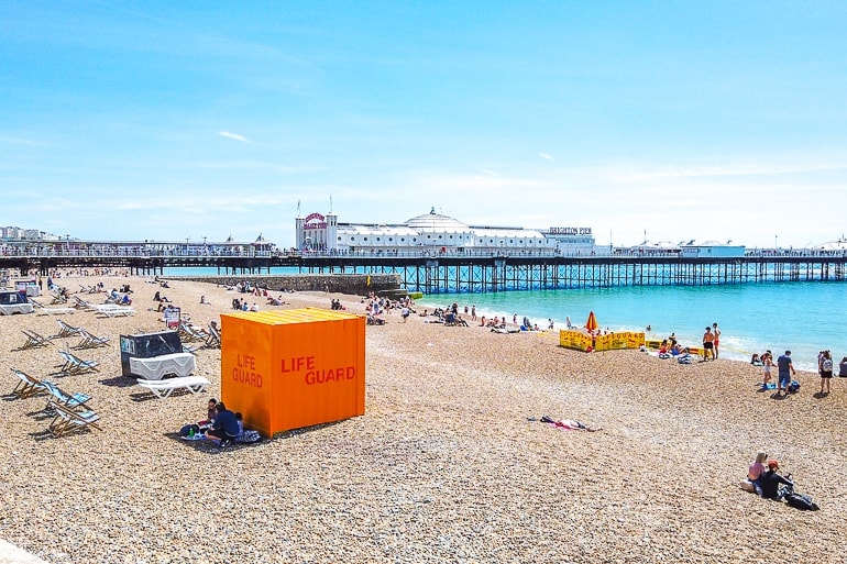 orange life-guarding stand on beach with pier in background