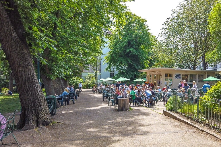 Menschen sitzen in Cafe mit Bäumen in der Umgebung