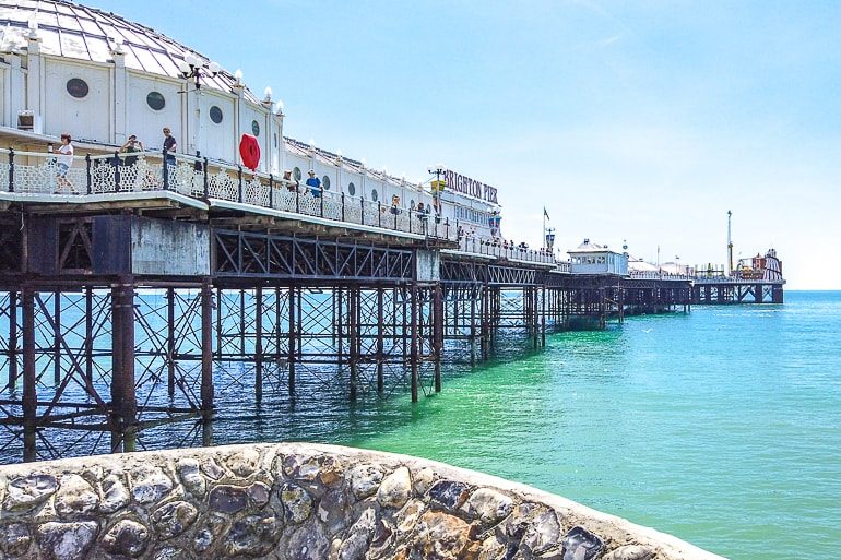 historic pier with wooden supports above blue shoreline in brighton uk