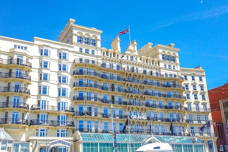 yellow hotel with balconies overlooking waterfront with blue sky above.