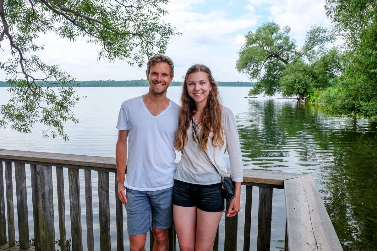 Mann und Frau posieren für ein Foto vor einem See und Bäumen.