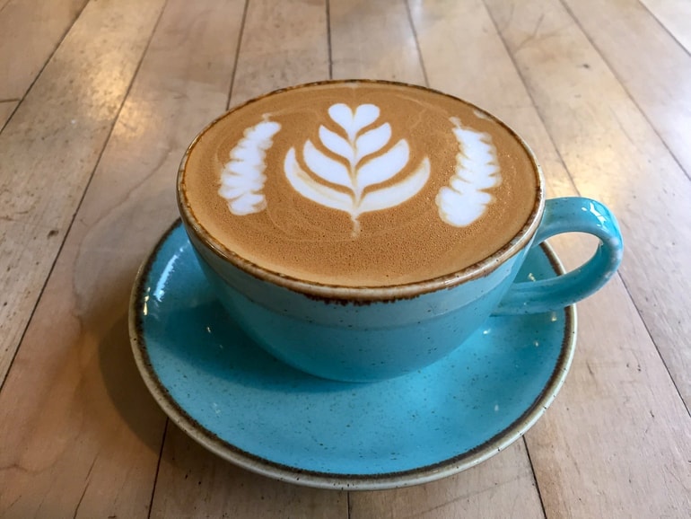 Kaffeetasse mit Kaffee und Latte Art auf Holztisch in Bristol.