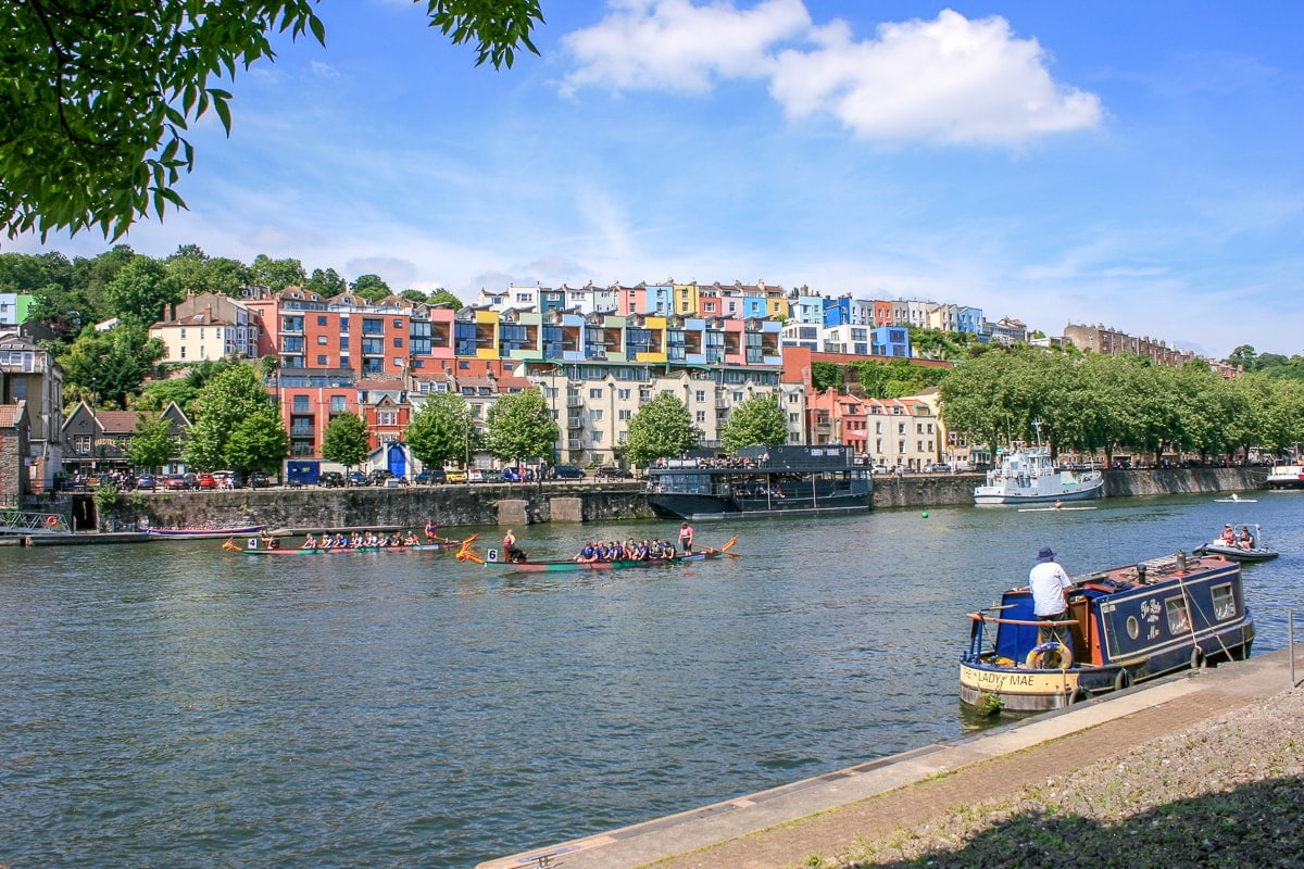 Boot im blauen Fluss mit bunten Häusern im Hintergrund Bristol Attraktionen
