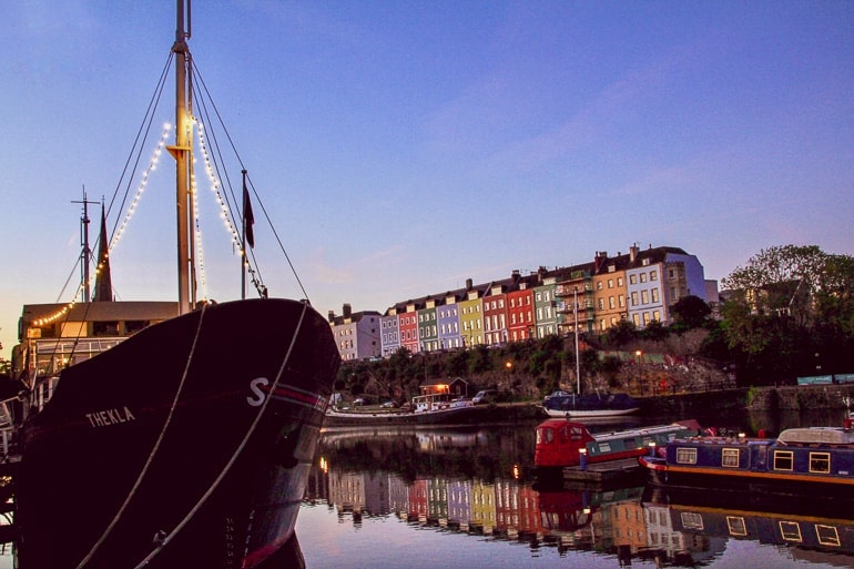 ship at night sitting in water with colourful houses behind bristol harbourside