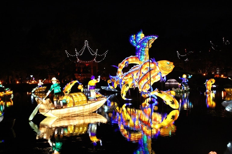lit up chinese fish light display at night over water at botanical gardens.