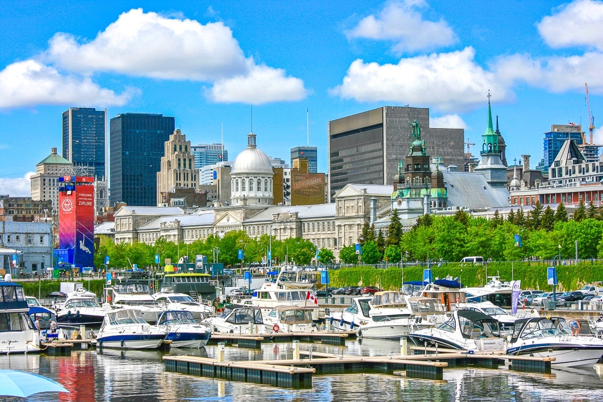 boats in water with historic buildings behind in harbour in montreal.