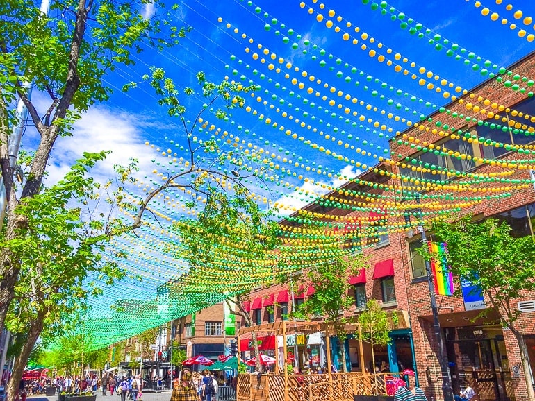 colourful beads strung above shop fronts over street in montreal village.