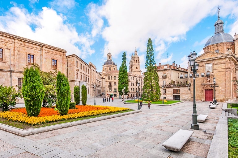 bright public square with gardens and towers behind salamanca spain