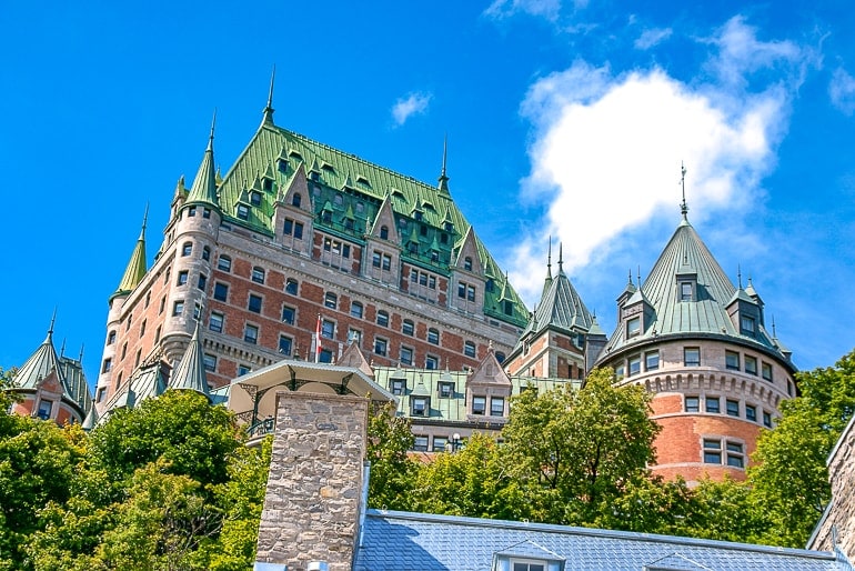 old castle looking hotel with green roof and trees below quebec city