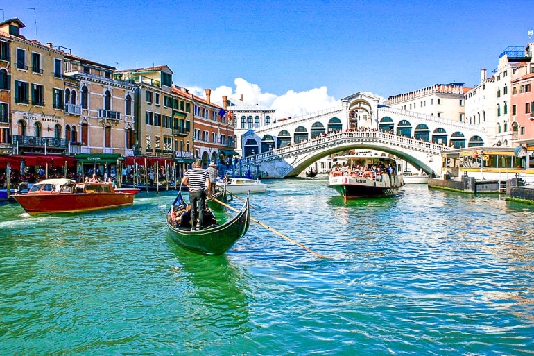 Brücke über Kanal mit Booten im Vordergrund in Venedig