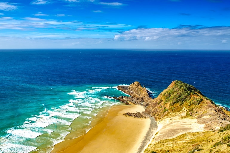 sandy beach point with blue ocean around cape reinga new zealand