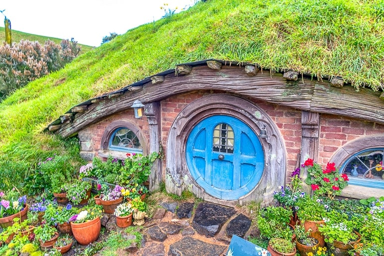 blue wooden door to small house in grassy hillside hobbiton new zealand
