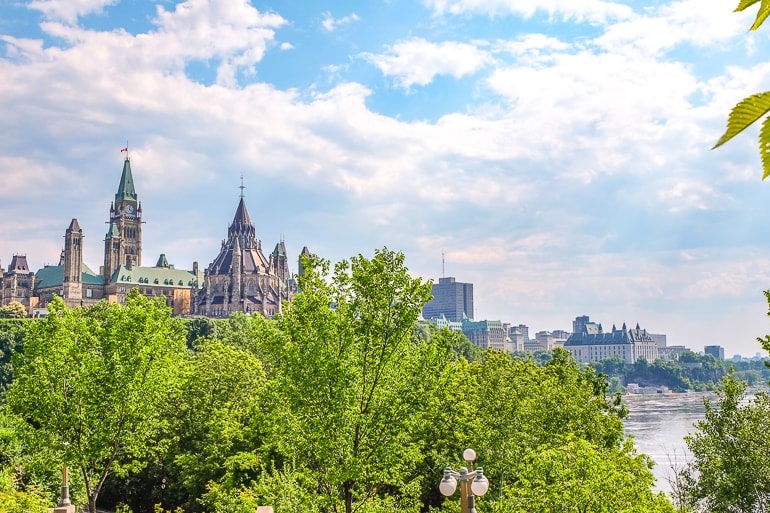 Kanadische Parlamentsgebäude mit grünen Bäumen und Fluss im Vordergrund Sehenswürdigkeiten Ottawa