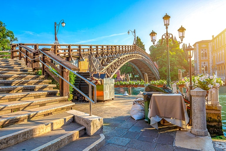 wooden bridge over canal with steps and sunshine venice italy