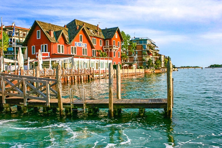 Anlegestelle aus Holz mit rotem Haus im Hintergrund Lido Venedig Italien