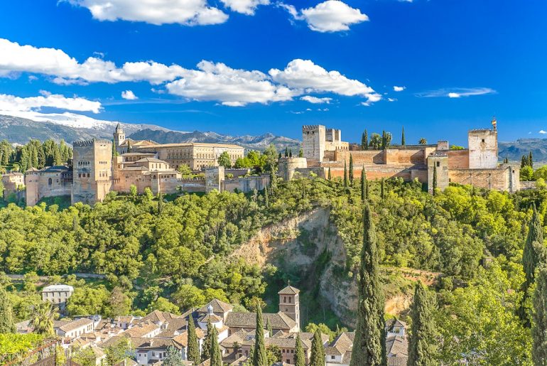 tan stone fortress on hill with green trees below alhambra granada top attractions in spain