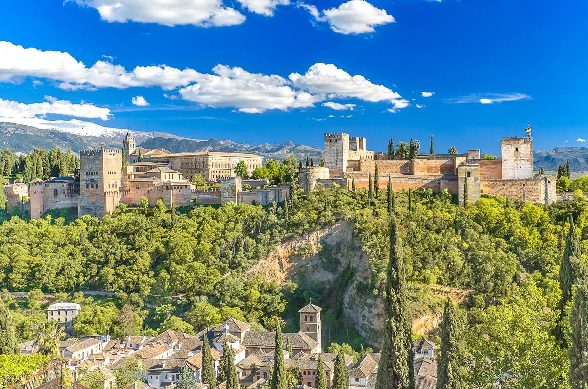Sandfarbene Burg aus Stein auf Hügel mit grünen Bäumen herum Alhambra Granada Spanien Sehenswürdigkeiten