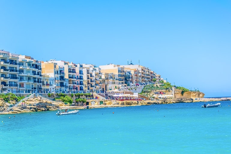 Blaues Meer mit Gebäuden entlang des Wassers im Hintergrund in Marsalforn Gozo