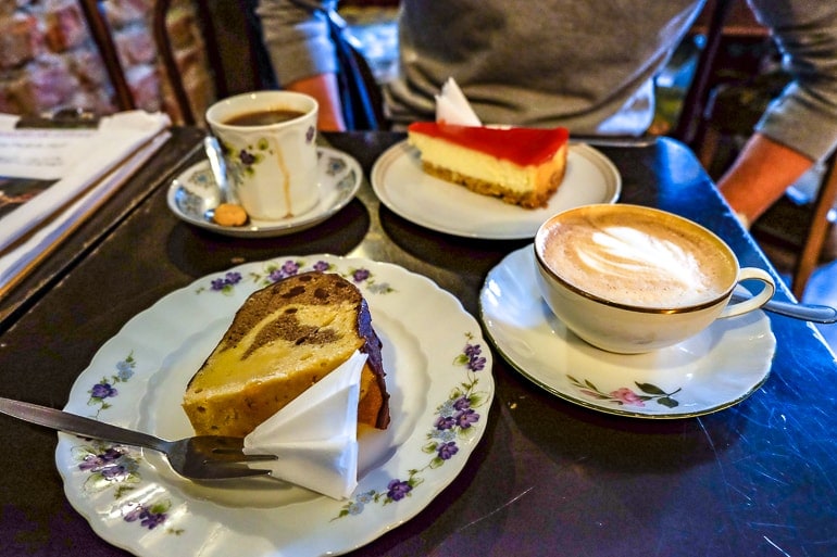 Zwei Stück Kuchen mit Kaffeetassen auf schwarzem Tisch in Café in München