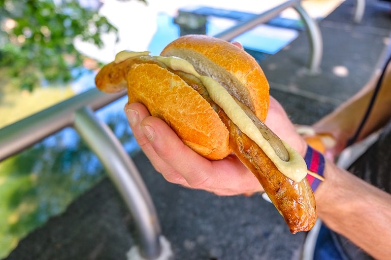Thüringer Bratwurst in Brötchen mit Senf gehalten von Hand