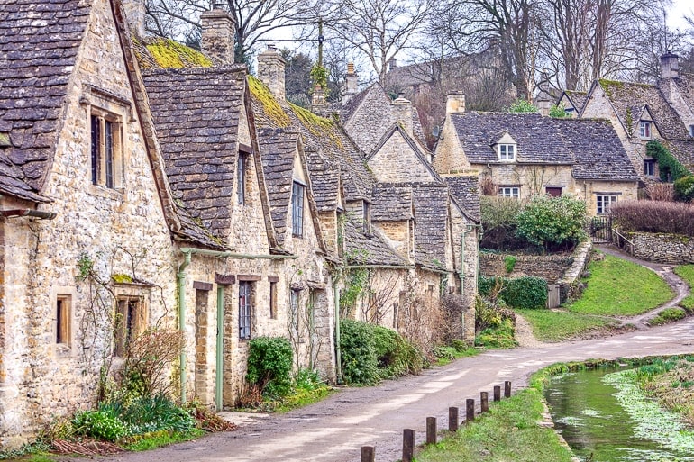 grey stone cottages with walking path in village in cotswolds