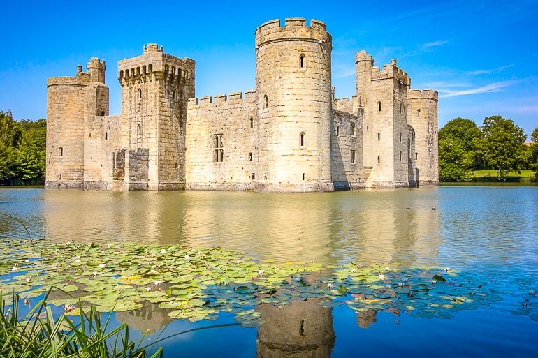 large castle with moat in front reflecting off water bodiam castle