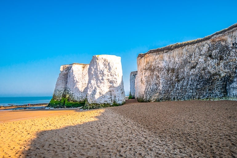 white stone cliffs with beach below and blue sky behind in botany bay