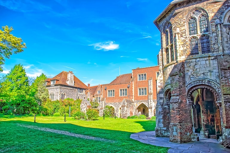 stone abbey with houses behind and green gardens in canterbury day trips from london