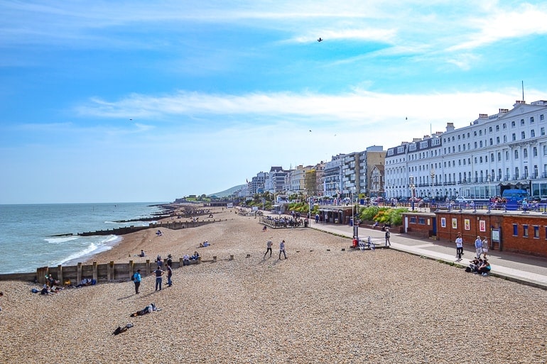 stone beach with city buildings and boardwalk in distance in eastbourne uk