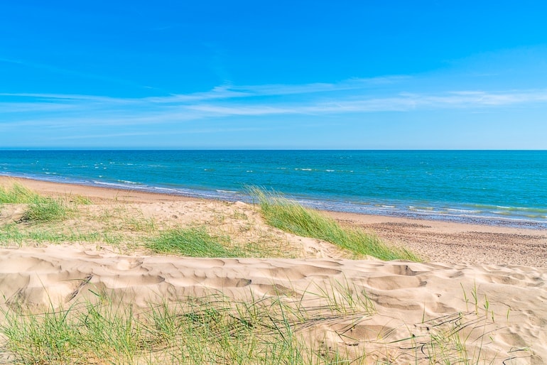 Sanddünen mit grünem Gras und blauem Meer im Hintergrund Camber sands