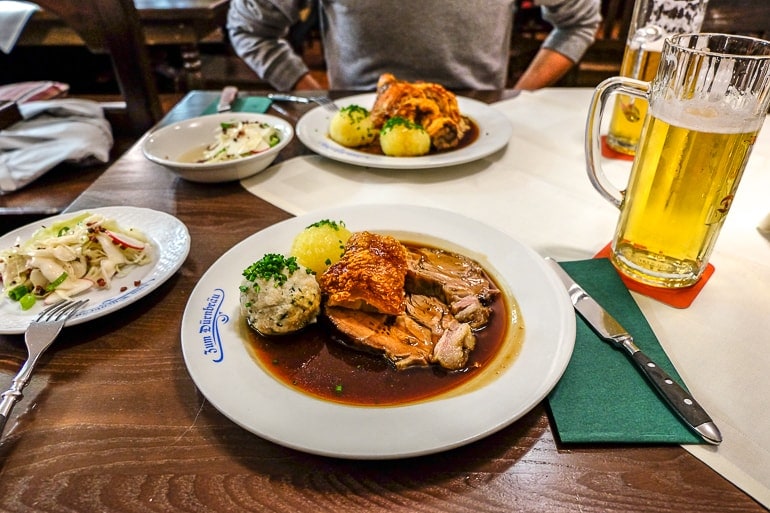 two plates of pork knuckle and potatoes with beer in bavarian restaurant