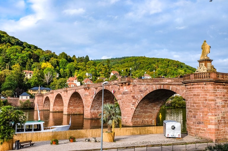 red arch bridge over river with green trees behind heidelberg germany