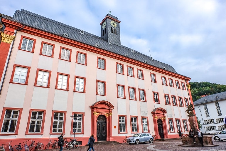 Rotes und weißes Universitätsgebäude mit Uhr in Altstadt von Heidelberg