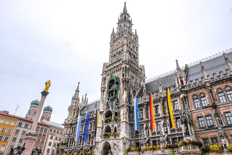 old town hall tower with clock and flags hanging off in marienplatz.