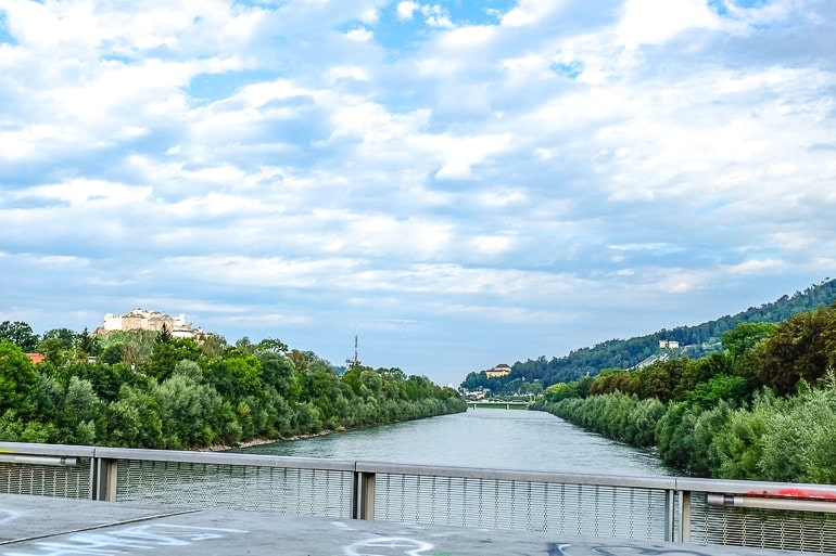 Blauer Fluss von Brücke aus fotografiert mit Festung und Bergen im Hintergund.