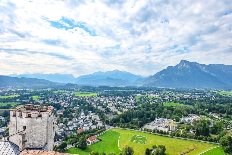Grünes Feld mit Häusern daneben und Bergen im Hintergrund in Salzburg.
