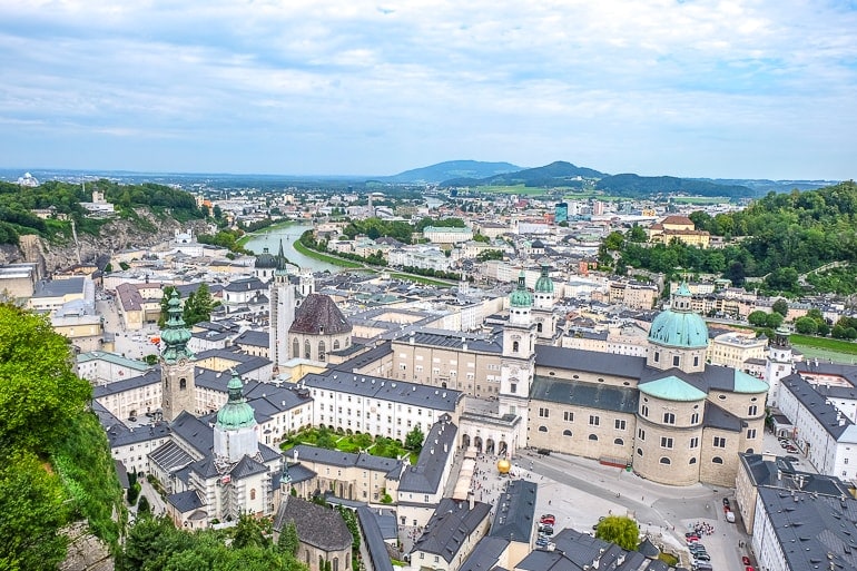 large cathedral with green domes and old town buildings around in salzburg austria