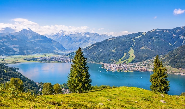 Blauer See mit kleiner Stadt am Seeufer und Bergen im Hintergrund Zell am See Österreich