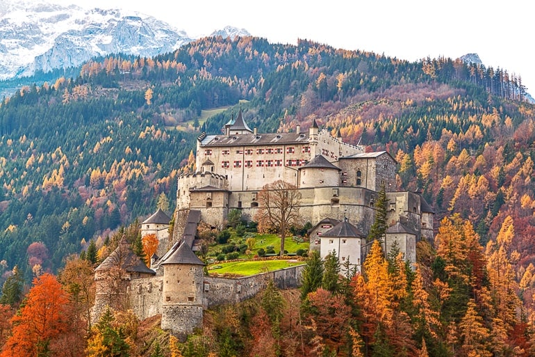 Alte Burg aus Stein auf Hügel mit Bäumen mit bunten Blättern herum