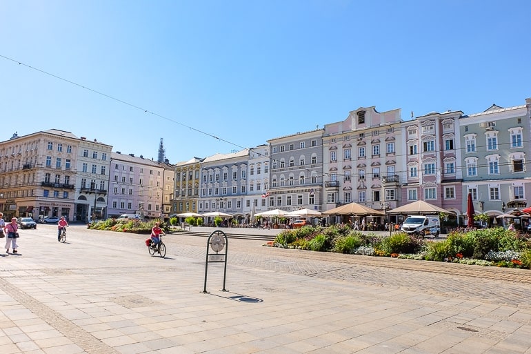 pastel buildings on city square with cafes and people walking in linz austria