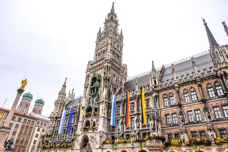 tall clock tower of munich town hall with flags
