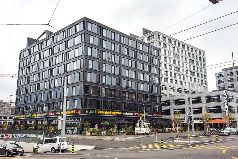 Schwarzes Hotelgebäude mit vielen Fenstern an Straßenecke.