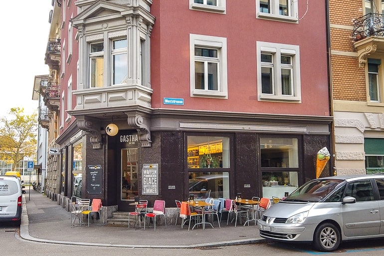 Kleines Cafe an Straßenecke mit Gasthaus im Haus und Autos vor Gebäude.