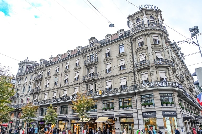 Hotel an Ecke von geschäftiger Straße in Zürich mit Läden im Erdgeschoss.