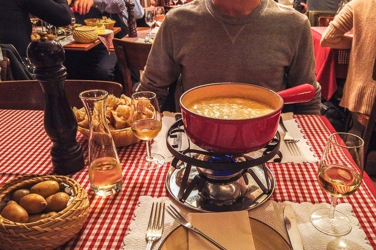 Roter Fondue Topf auf Tisch mit roter Tischdecke, Wein und Essen in Zürich