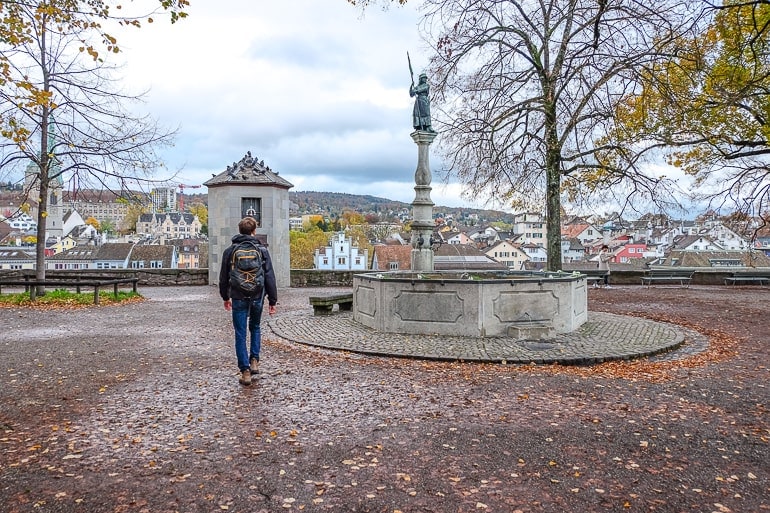 man walking through park with fountain lindenhof hill zurich