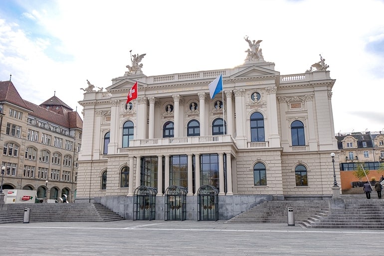 grand opera house with flags and open square in front in zurich