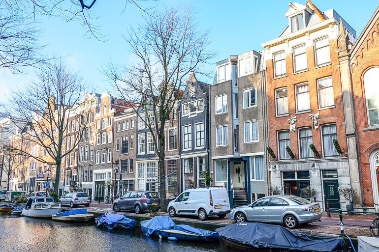 Bunte Häuser mit Fenstern und geparkten Autos davor in Amsterdam